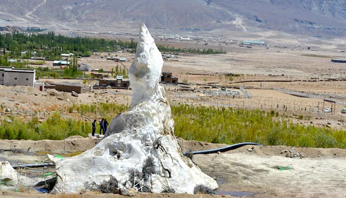 An ice stupa in Phyang village is shown. The area below is shown to have turned green with the help of ice melt in the past three years