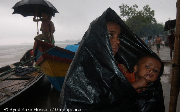 A woman with her child waits for relief in heavy rain. Local people have lost their homes and jobs as a result of the floods. The floods were caused by the change in the course of the waterway on the river Jamuna.