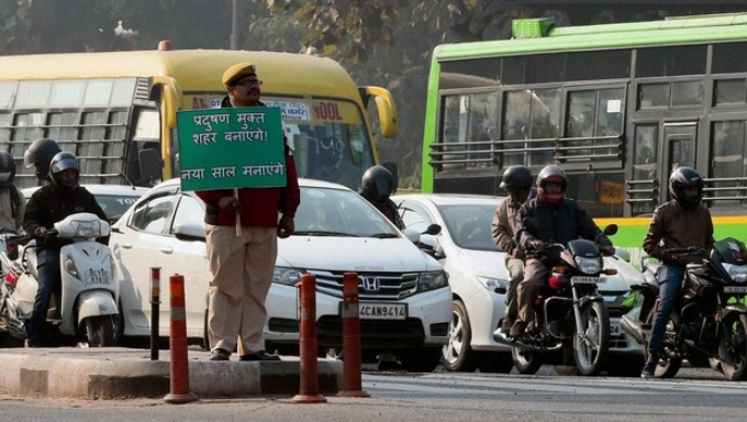 A policeman holding a sign that reads, “We’ll make it a pollution free city, we’ll enjoy the new year” (Image by Delhi government) 